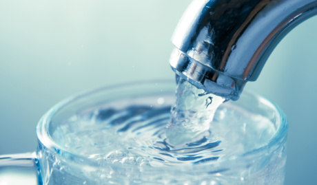 Close Up View Of Water Flowing From Tap Into Glass