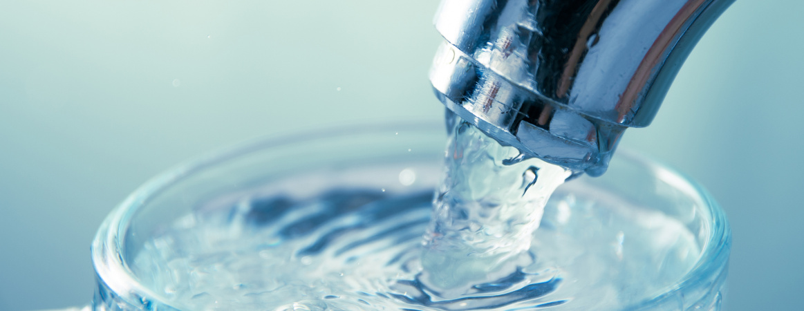 Close Up View Of Water Flowing From Tap Into Glass