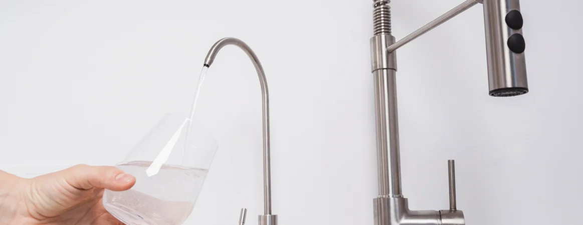 Person Pouring Filtered Water Into Glass Cup