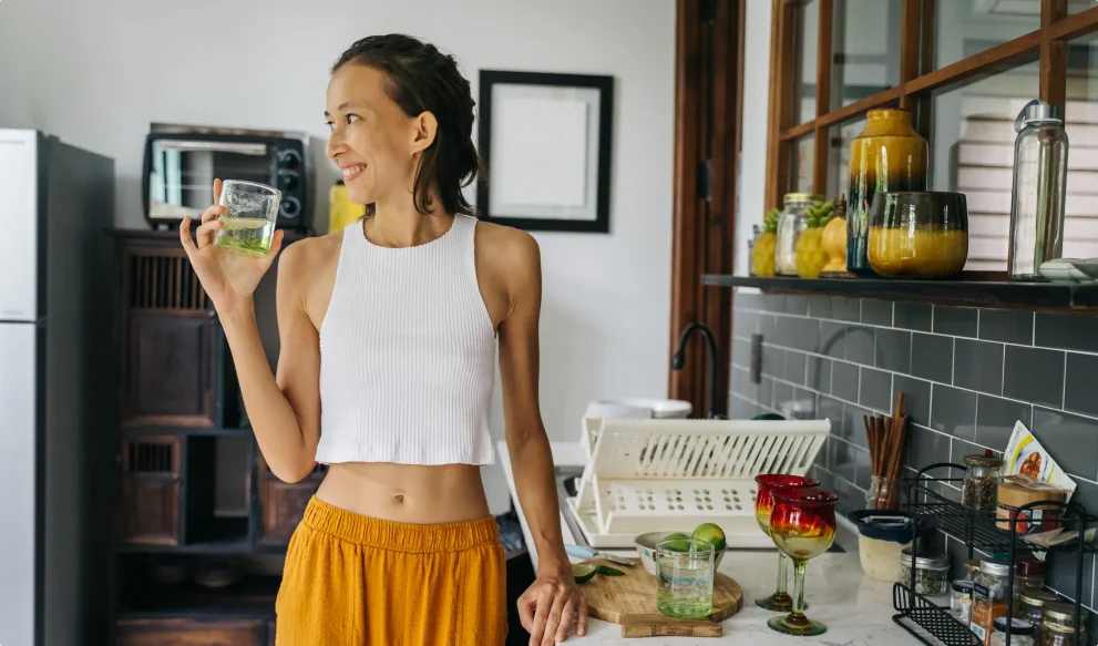 Young woman holding a glass of filtered water in kitchen